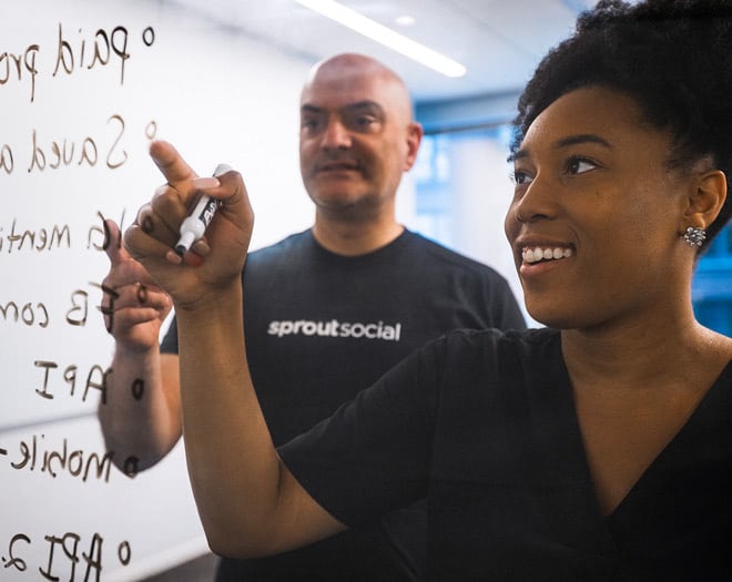 Sprout Social team members writing on a dry erase board with Post-It notes